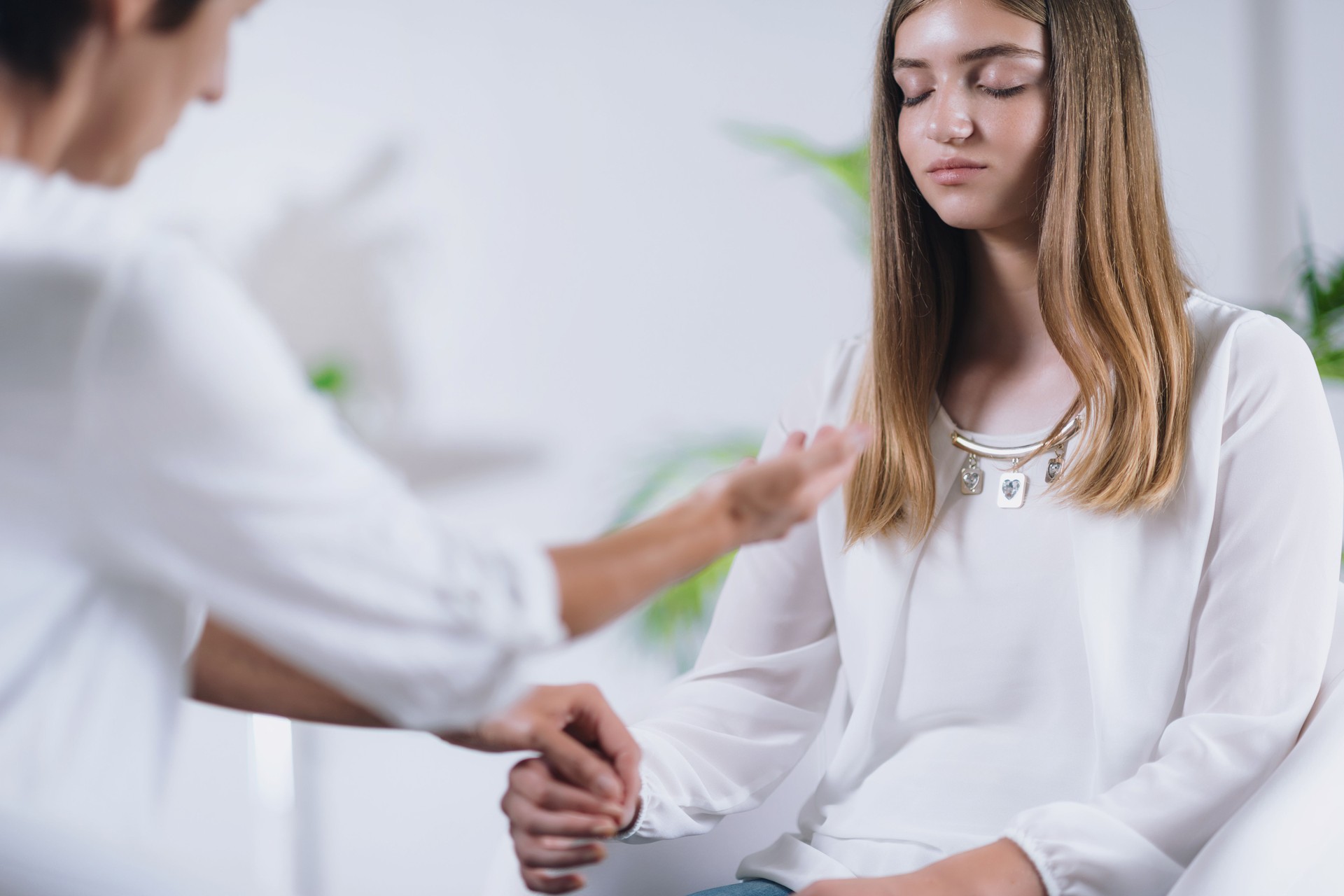 Female Therapist Holding Hands With Teenage Girl In Room